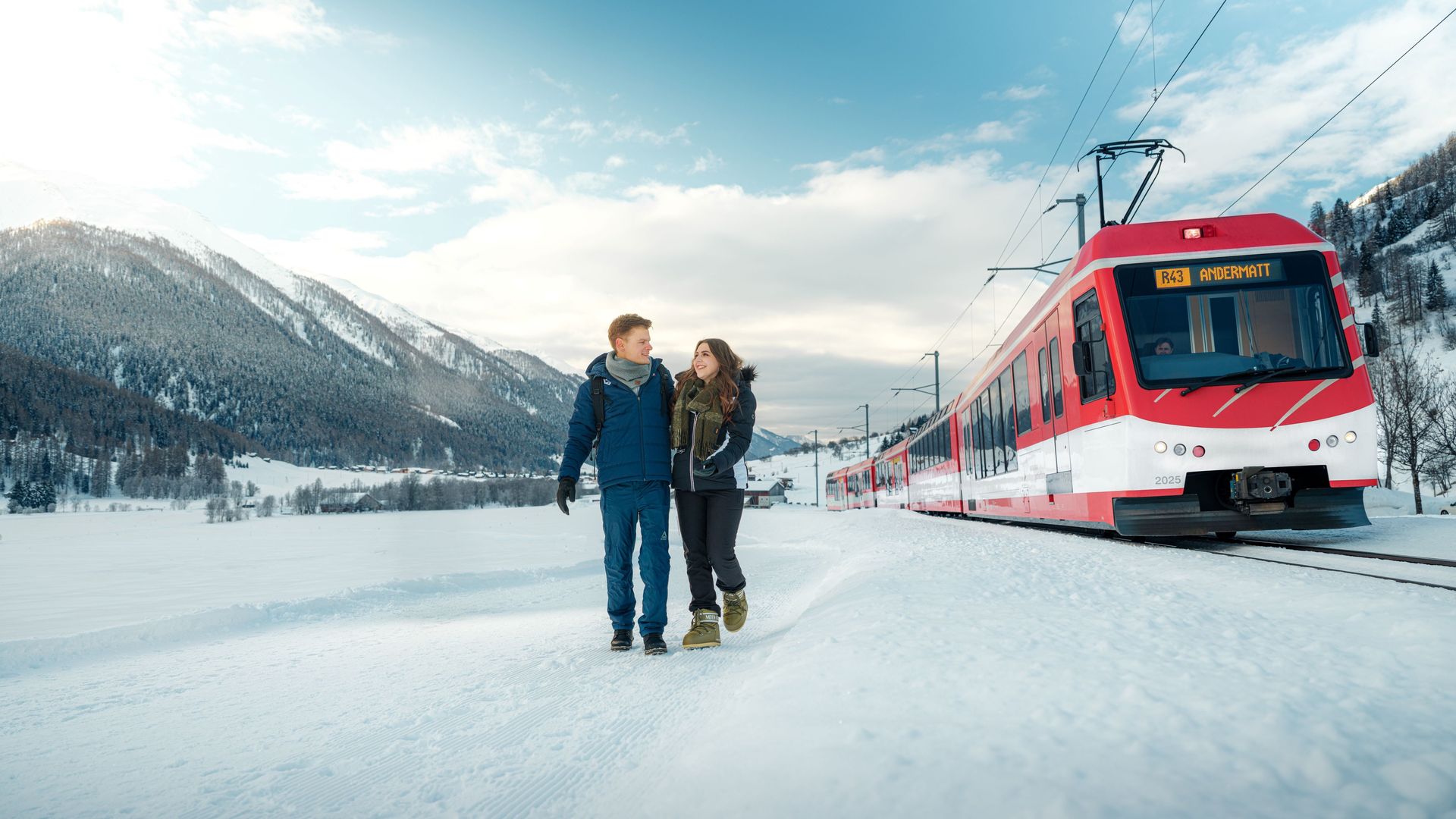 Two people hike through the snow in Goms