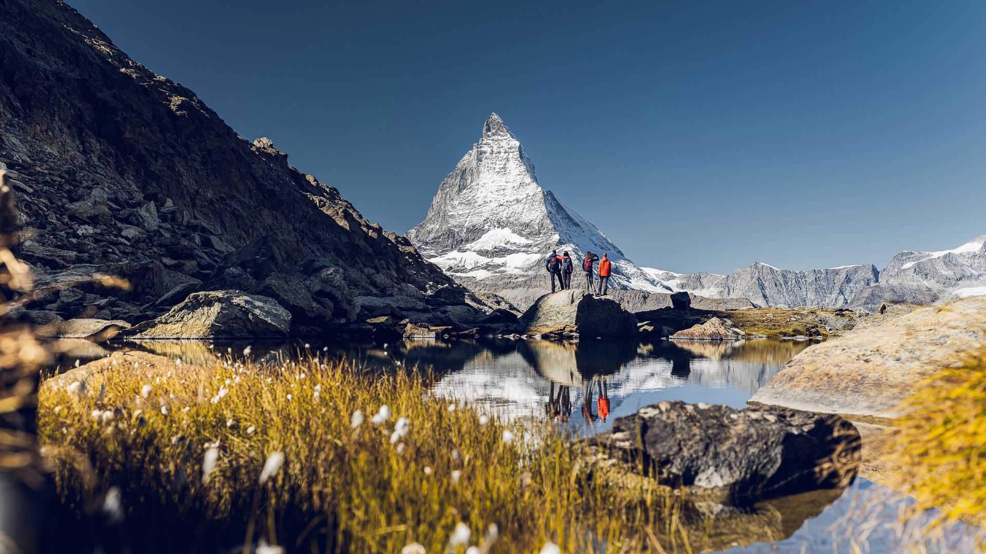 Randonneurs devant le Cervin, derrière le Riffelsee, lors d'une journée ensoleillée d'été.