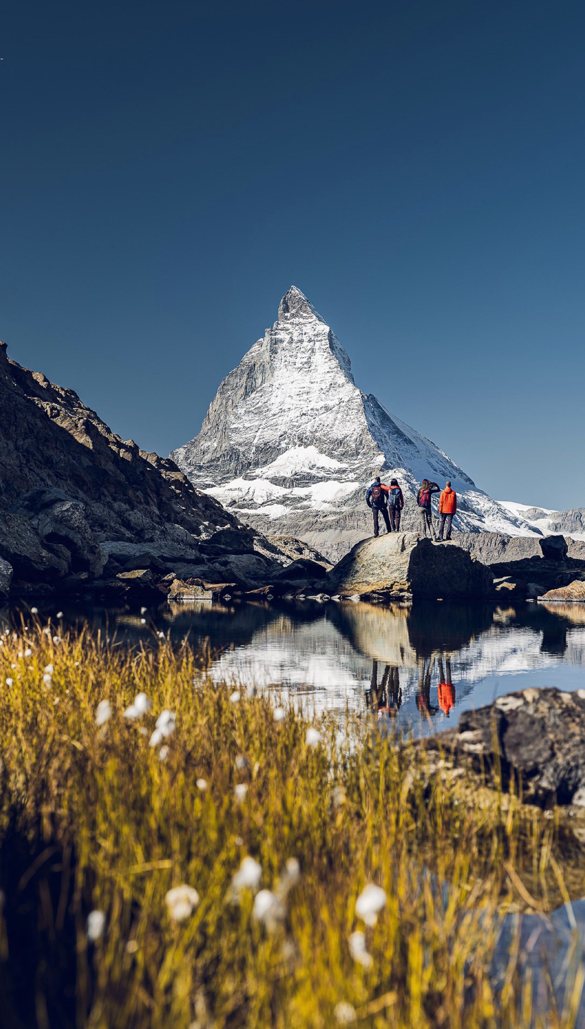 Hikers in front of the Matterhorn, behind the Riffelsee, on a sunny summer's day.