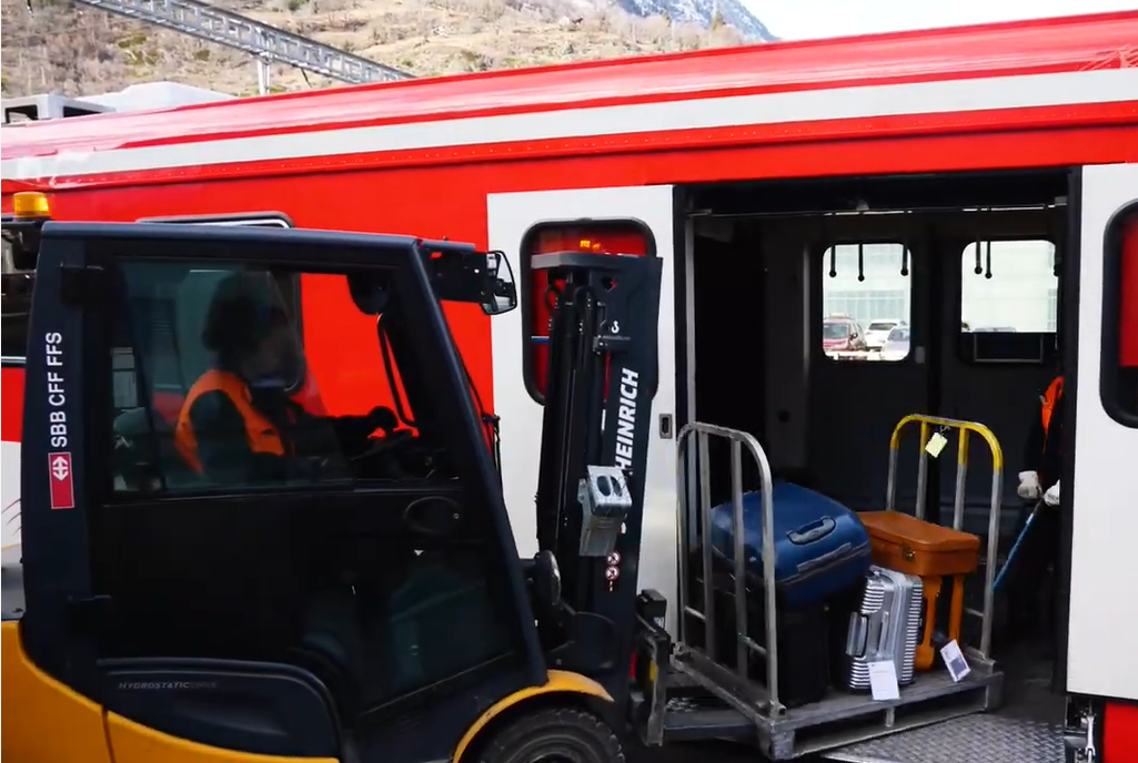 Das Gepäck wird mithilfe eines Hubwagens im Zug in Richtung Zermatt transportiert.