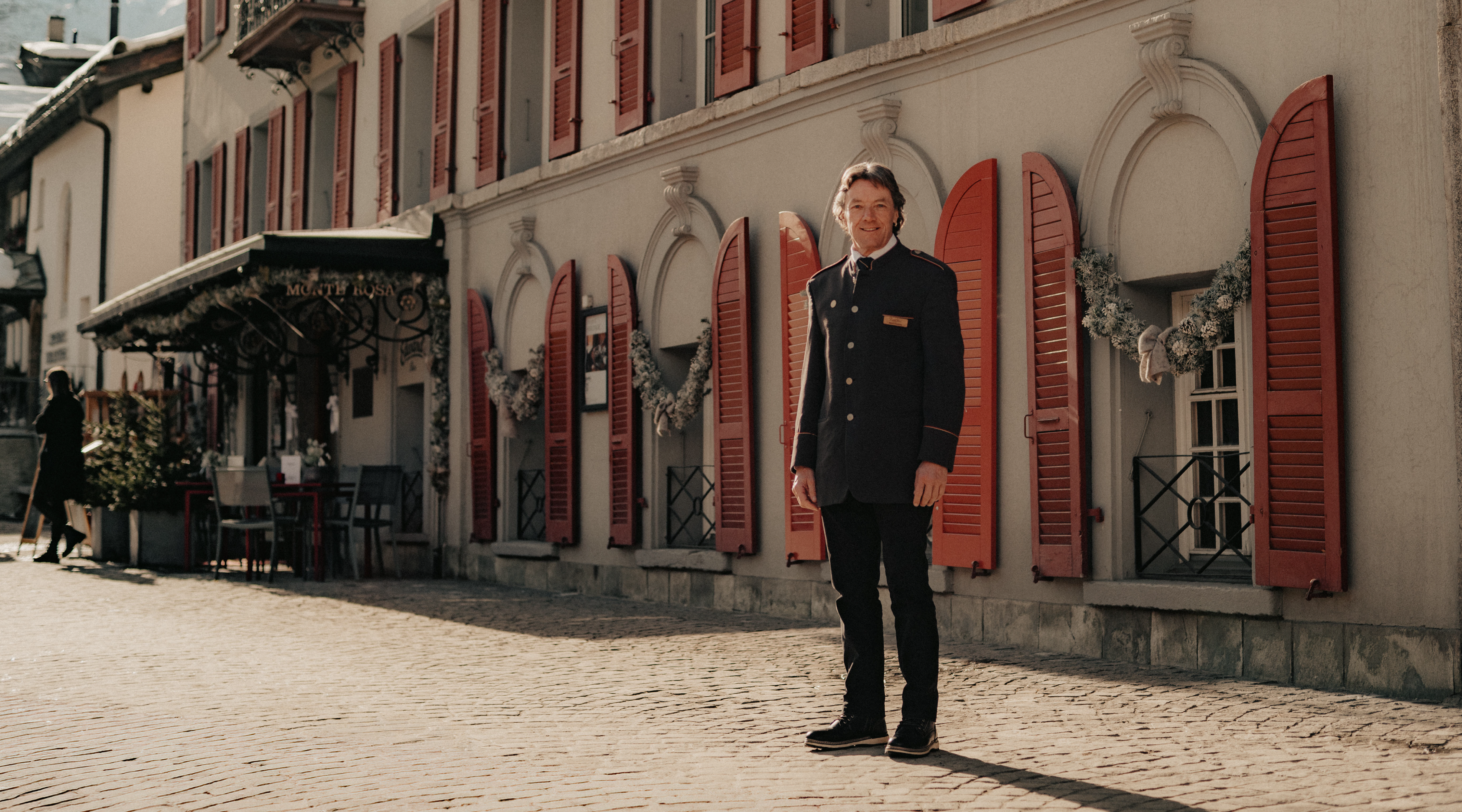 The NostalChic Class concierge awaits the guests outside the Monte Rosa Hotel, offering a warm welcome.