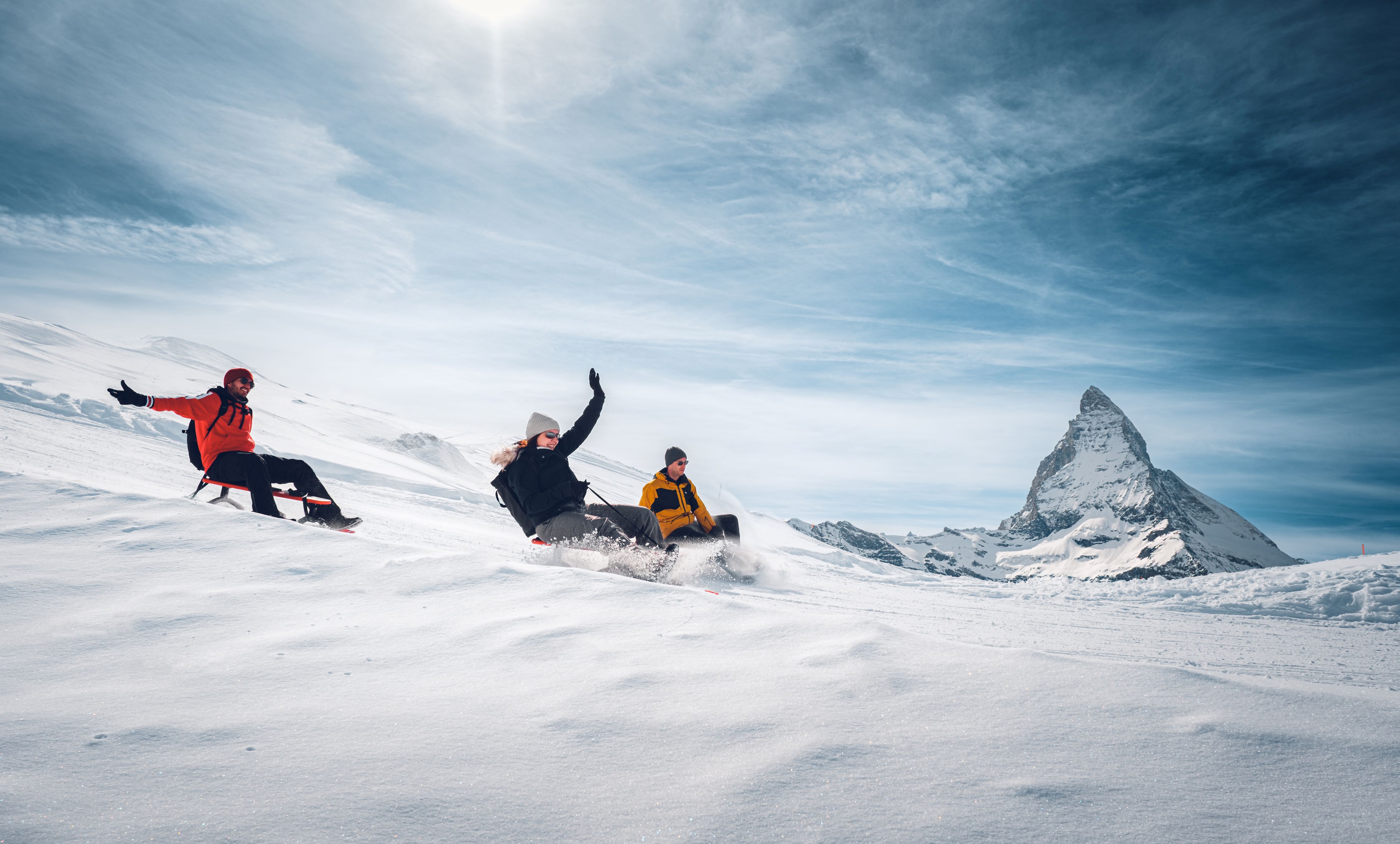 People are sledging, while in the background, the Matterhorn rises majestically, covered in snow.
