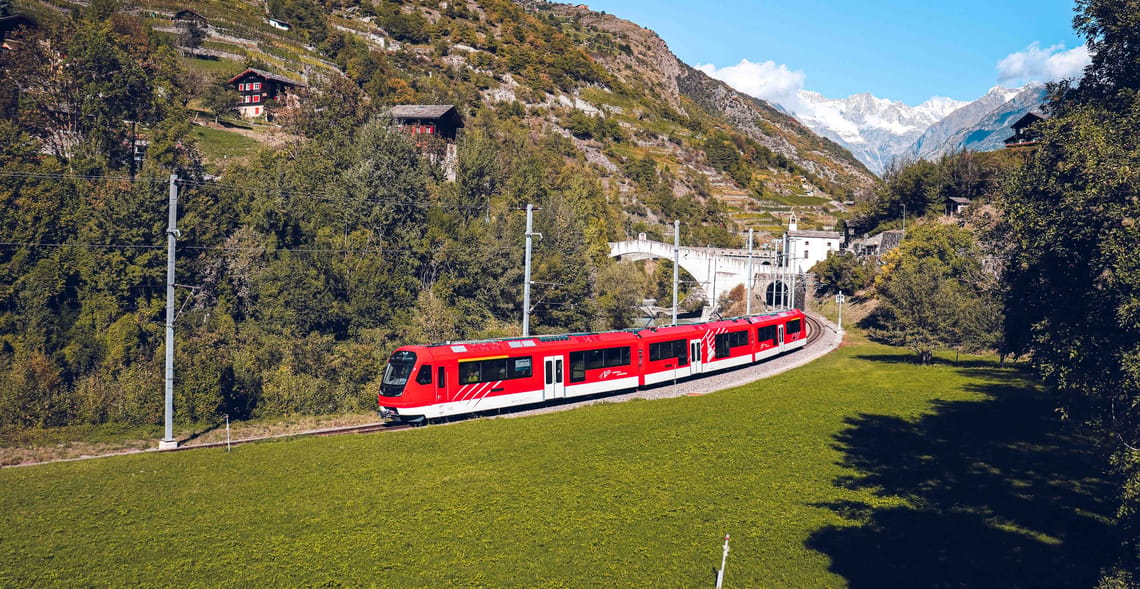 Orion Testfahrt im Mattertal 2023 Die Orion im Mattertal im Jahr 2023 an einem sonnigen Tag, während sie durch eine grüne Landschaft fliegt.