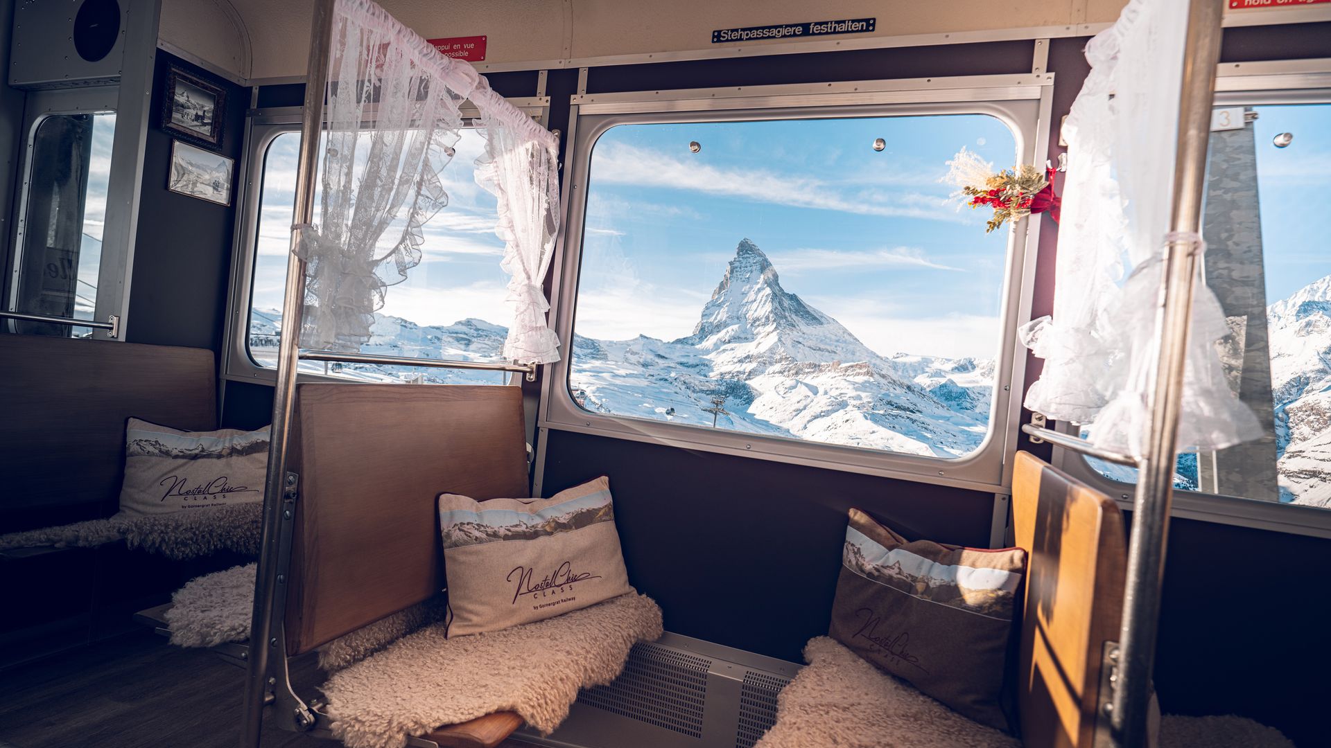 Der mit Kissen und Vorhängen geschmückte Waggon des NostalChic bietet eine gemütliche Atmosphäre. Aus dem Fenster zeigt sich das schneebedeckte Matterhorn unter einem blauen Himmel